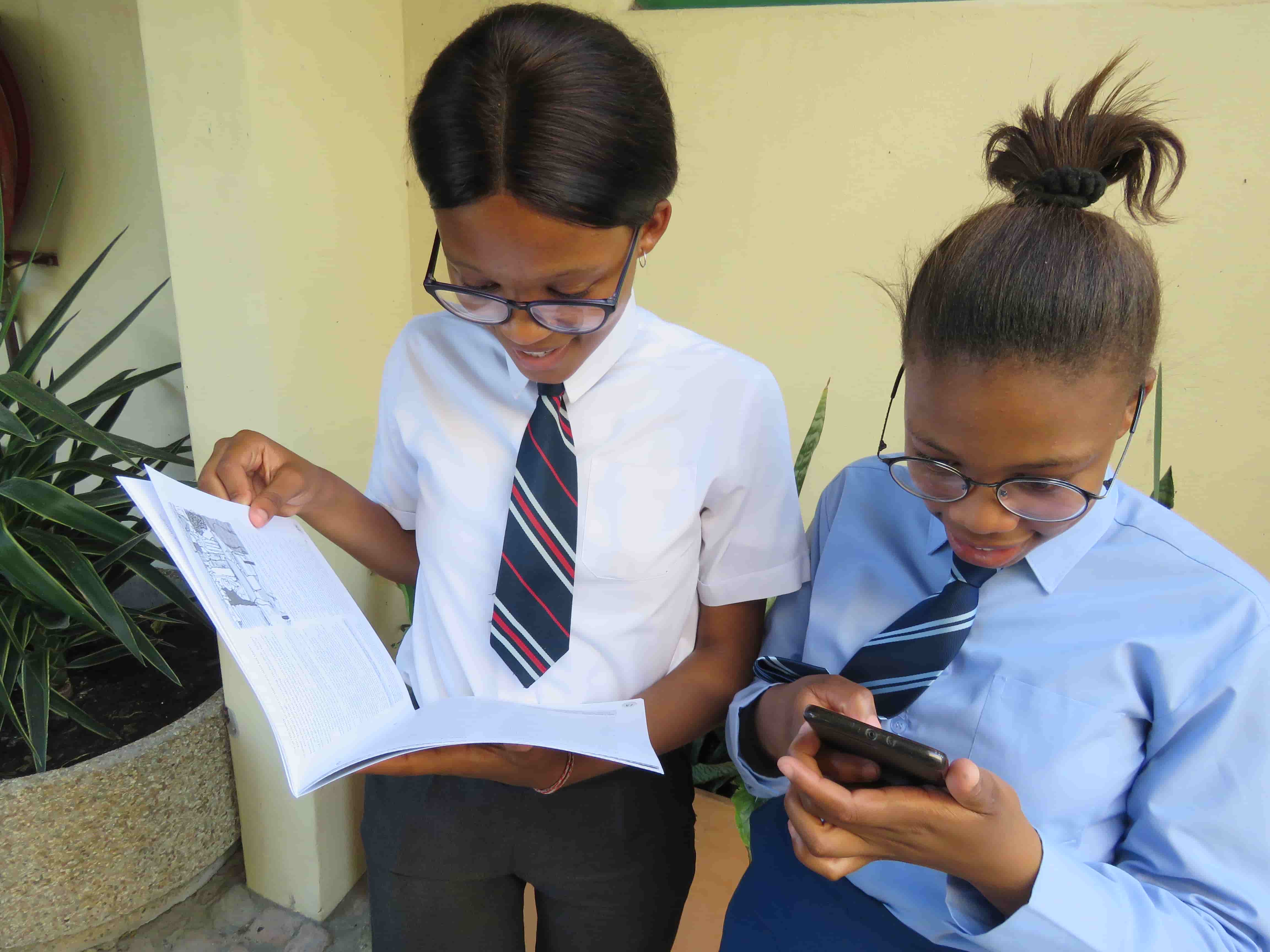 Two learners using a printed publication and a mobile phone